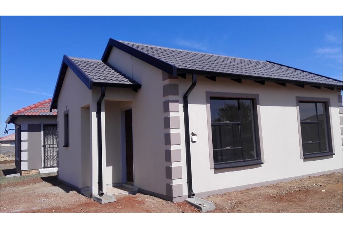 A modern single-story residential house featuring a tiled roof, painted exterior walls with decorative corner quoins, and black guttering.
