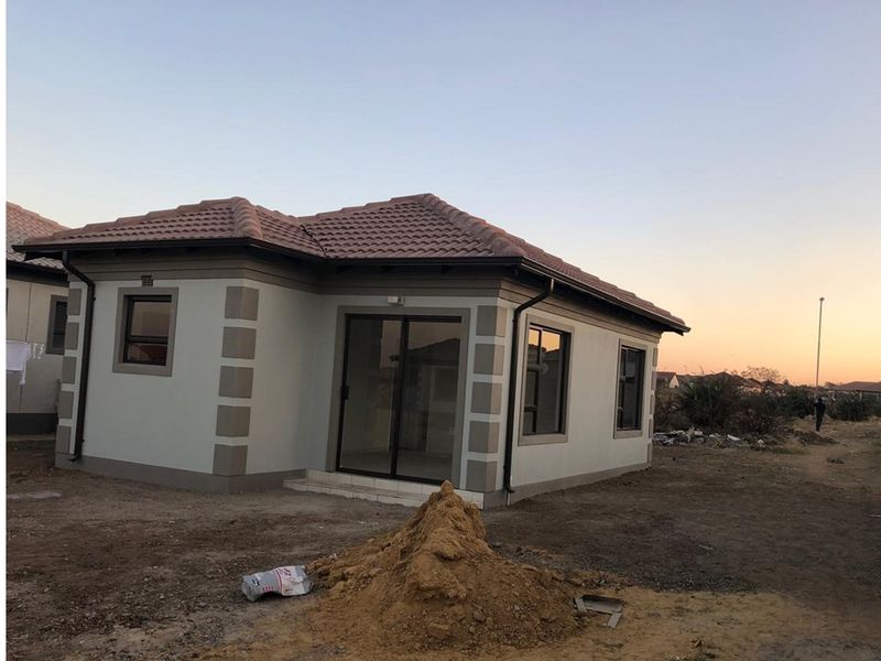 A view of the exterior front of a single-story residential house featuring a tiled roof, sliding glass doors, and perimeter window frames.