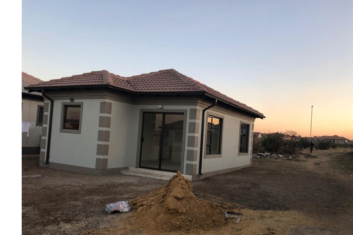 A view of the exterior front of a single-story residential house featuring a tiled roof, sliding glass doors, and perimeter window frames.