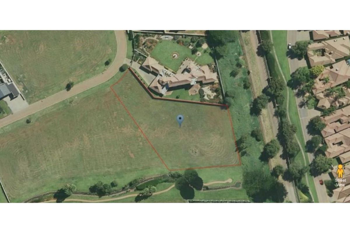 An aerial view of a vacant residential plot with marked boundaries, situated in a developed estate setting.
