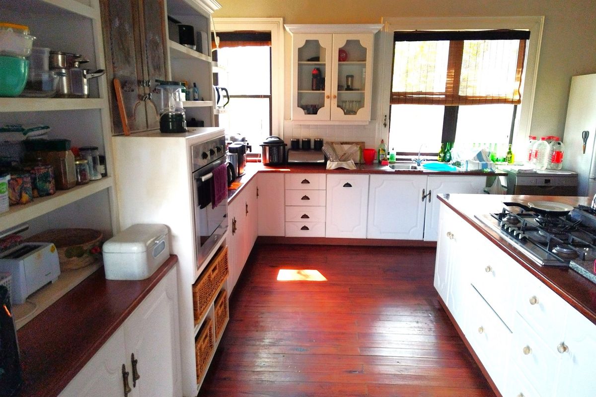 A functional kitchen featuring white cabinetry, warm wooden countertops, hardwood flooring, and integrated cooking appliances, offering a classic and practical layout.