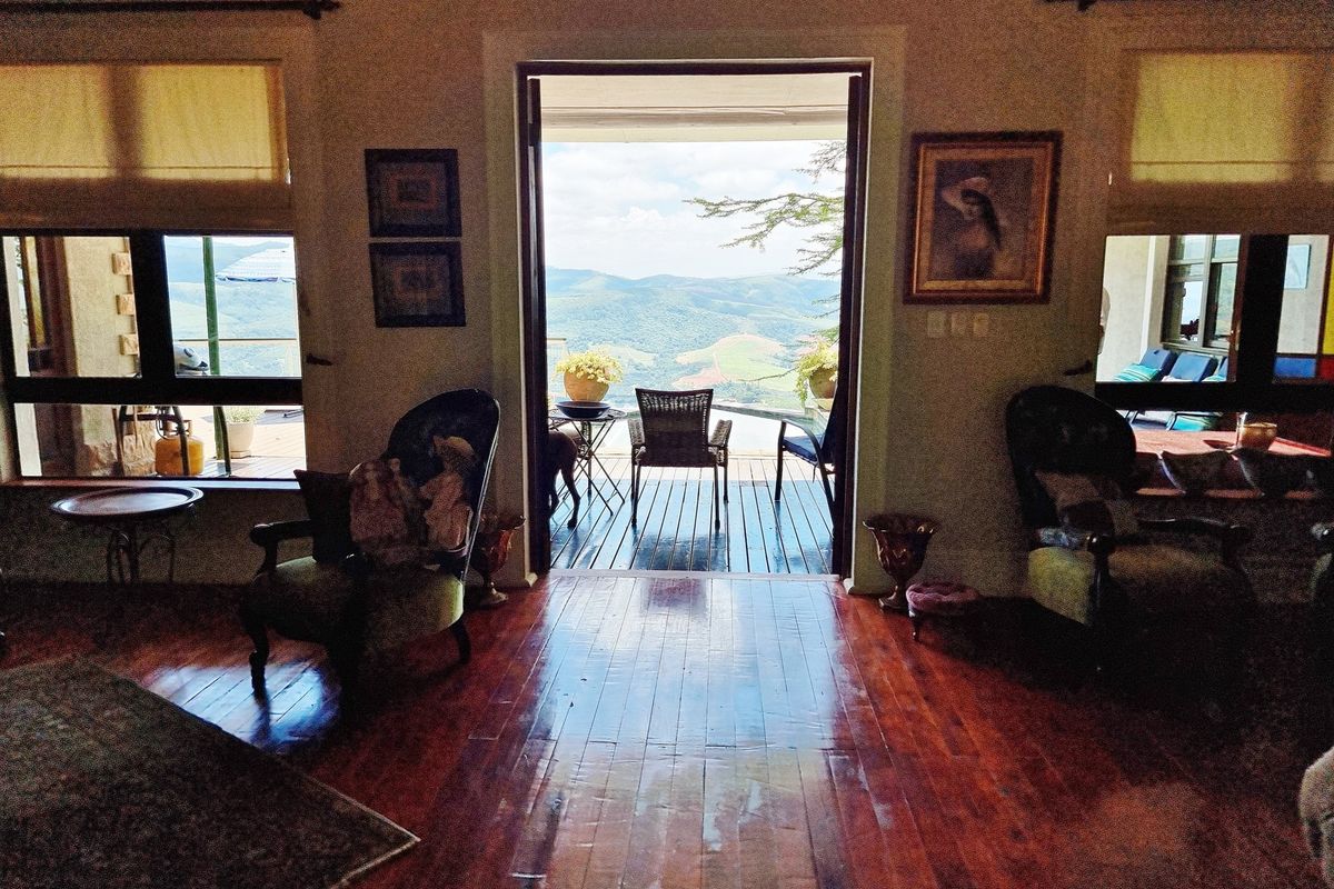 Spacious living area featuring rich hardwood flooring and large glass doors opening onto a timber deck with expansive mountain views.
