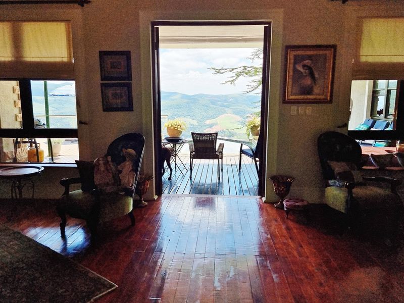 Spacious living area featuring rich hardwood flooring and large glass doors opening onto a timber deck with expansive mountain views.