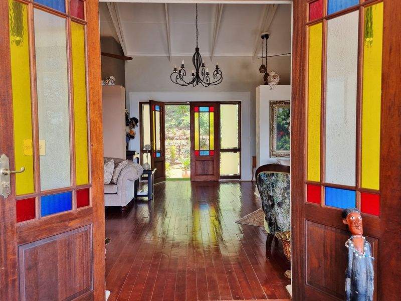 Inviting entrance hall featuring polished timber flooring, vaulted ceilings with exposed rafters, and classic stained glass timber doors leading to the rear garden.