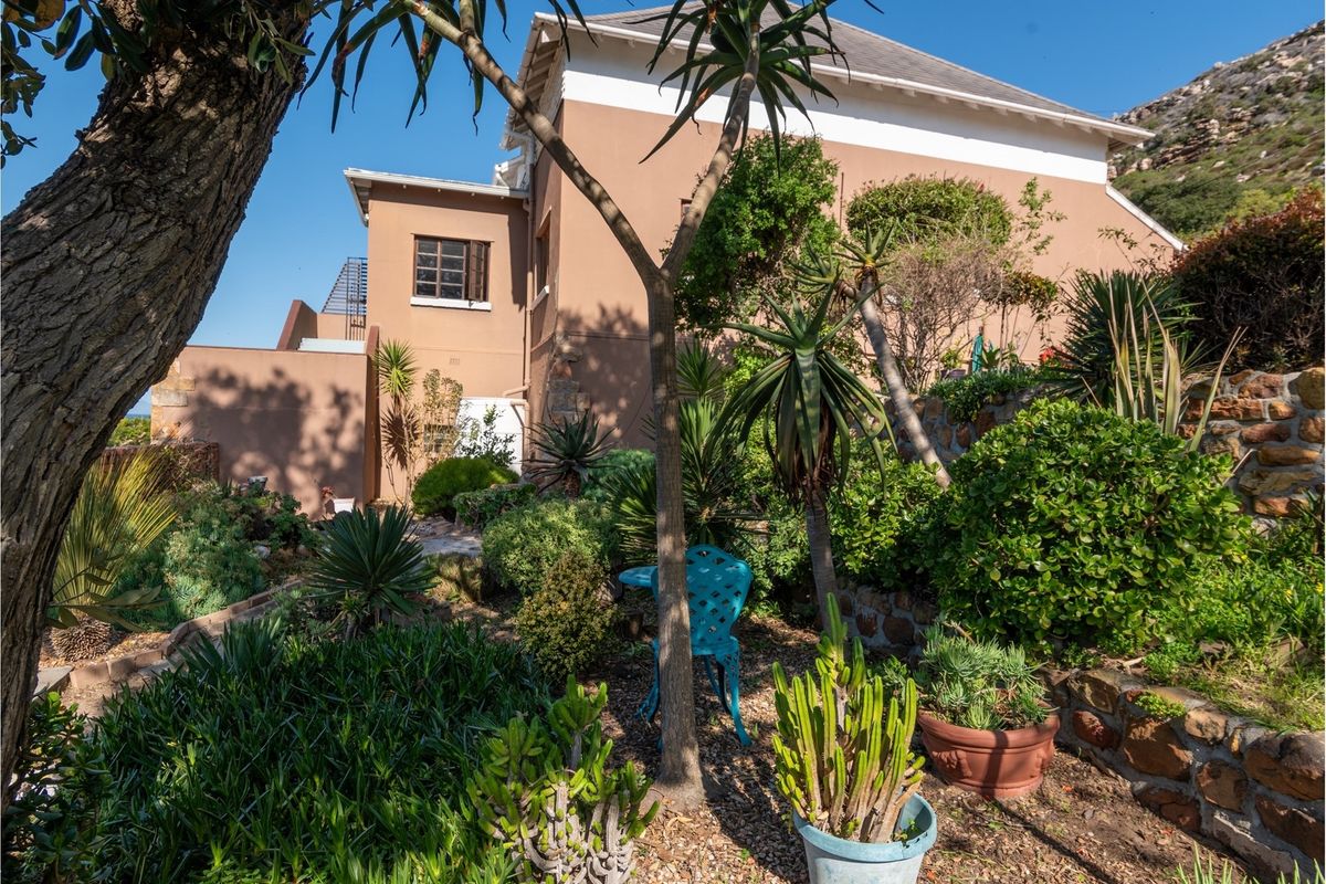 A view of the rear elevation of the house featuring a well-established landscaped garden with stone retaining walls and mature plantings.