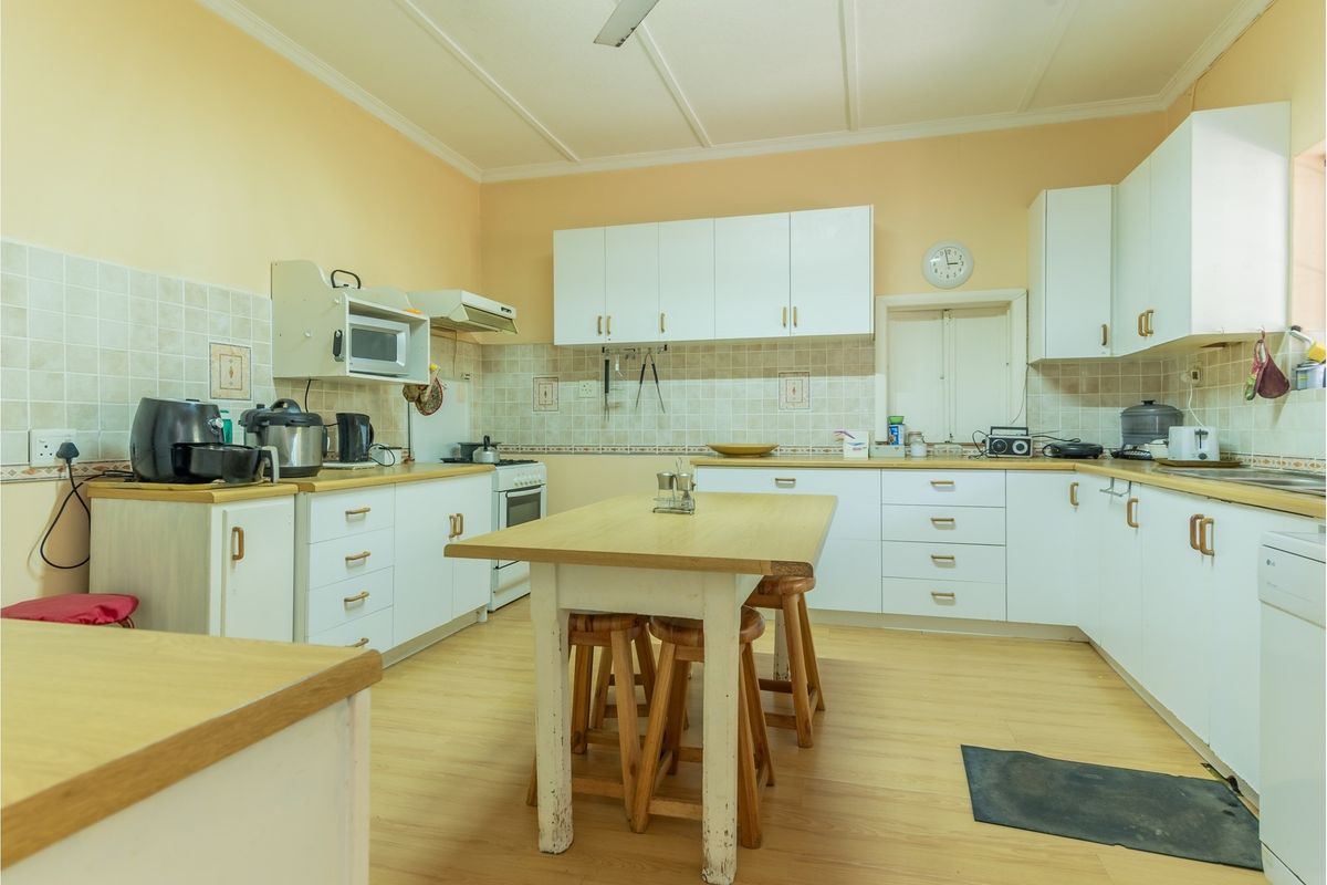 A functional kitchen featuring white cabinetry, tiled backsplash, laminate countertops, and a central island, offering a practical layout with potential for modern updates.