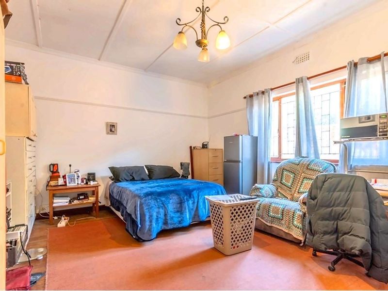 A bedroom featuring a classic picture rail, ceiling rose, and security bars on the window, offering a functional space with potential for cosmetic updates.