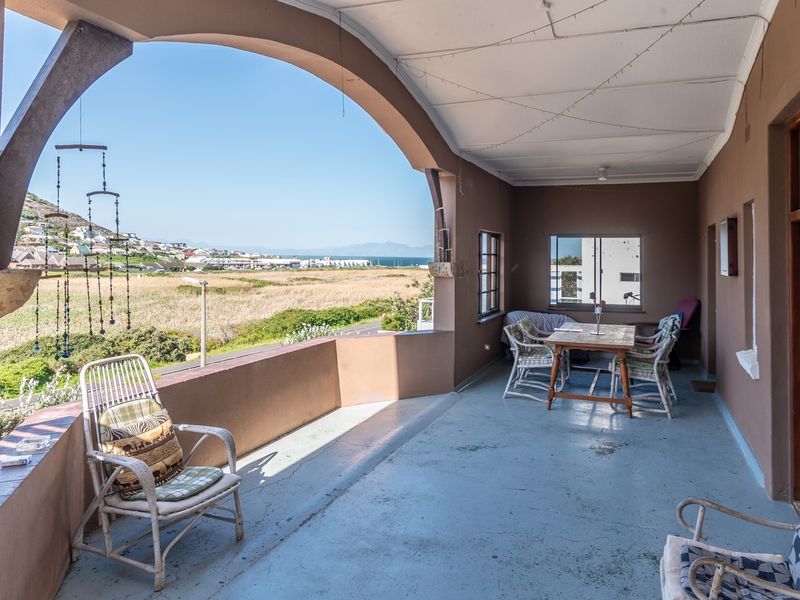 Spacious covered patio featuring arched architectural details and expansive views of the surrounding landscape and distant coastline.