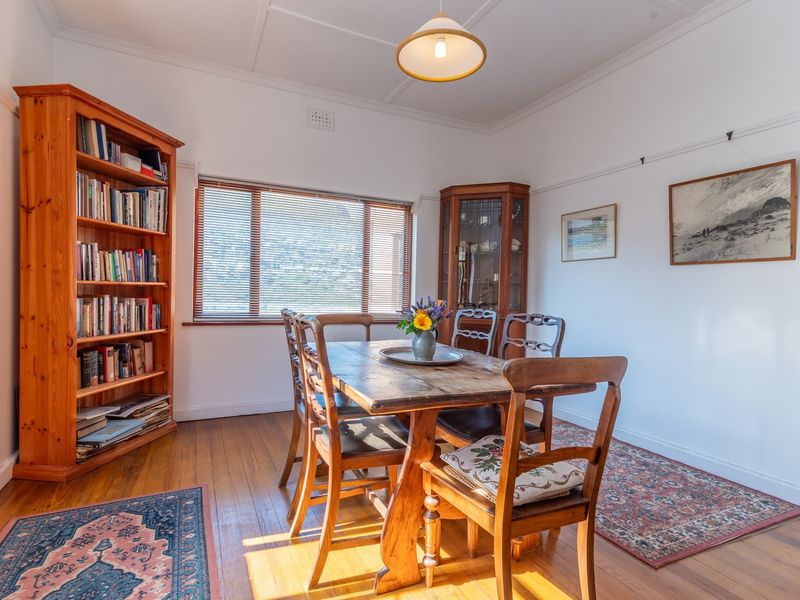 A bright dining room featuring polished timber flooring, classic picture rails, and natural light through venetian blinds.