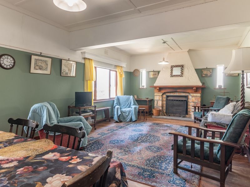 Spacious living room featuring a prominent stone fireplace, timber flooring, and classic picture rails, offering a warm and traditional atmosphere.