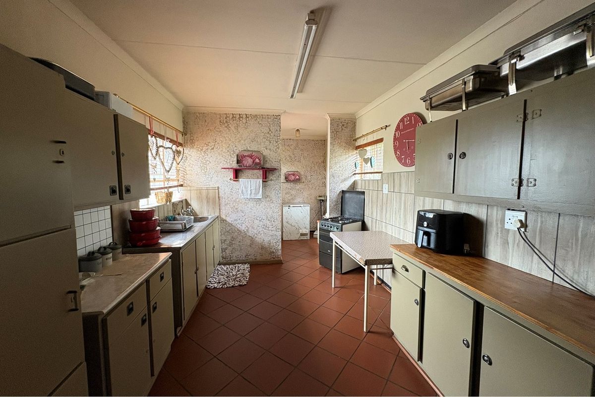 A functional kitchen featuring dated cabinetry, tiled flooring, and a freestanding stove, offering a practical layout with potential for modernization.