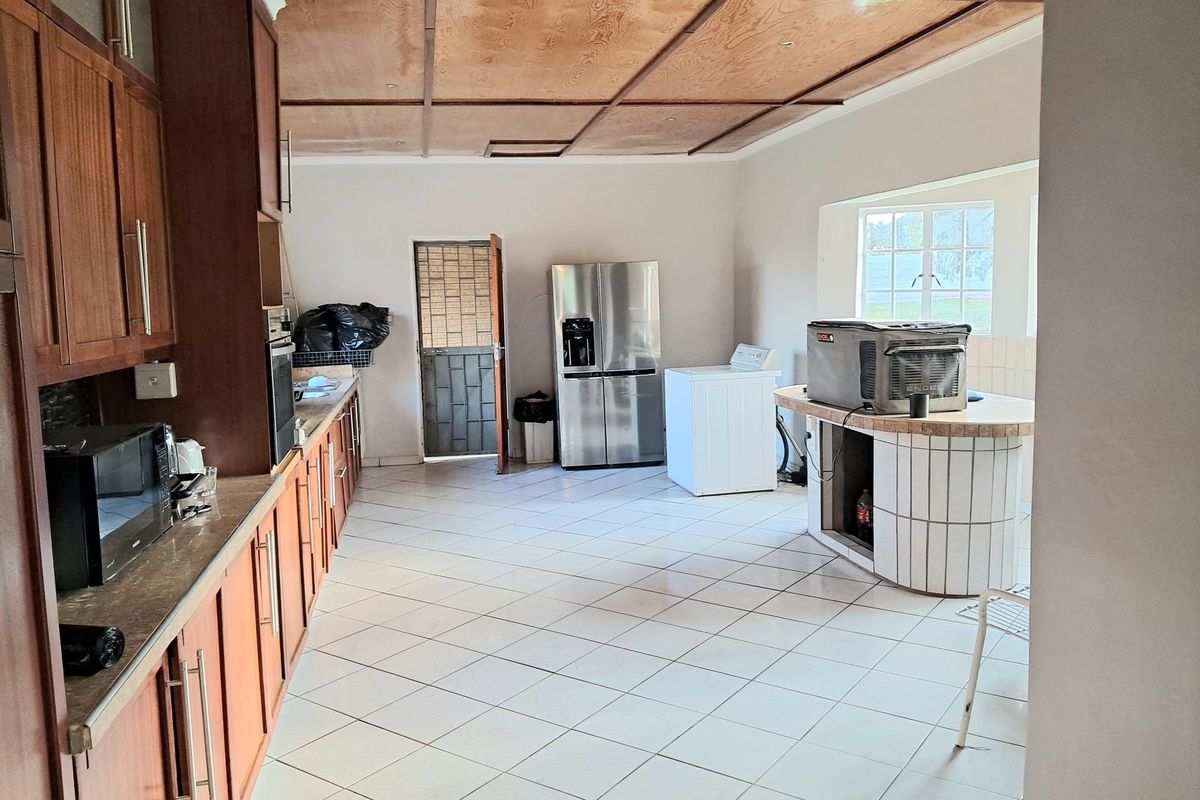 Spacious kitchen featuring extensive built-in cabinetry, a central tiled island, and timber panel ceiling, offering a functional layout with direct exterior access.