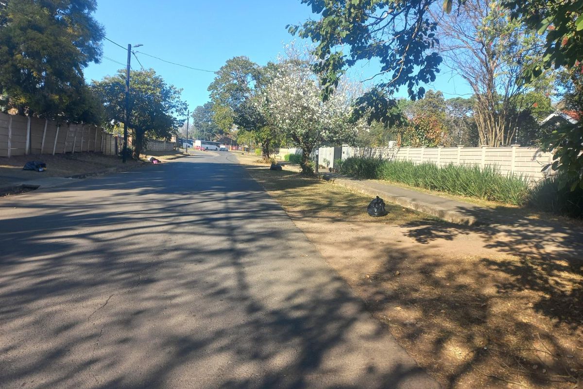 A view of the residential street showing the paved road, sidewalk, and boundary walling.