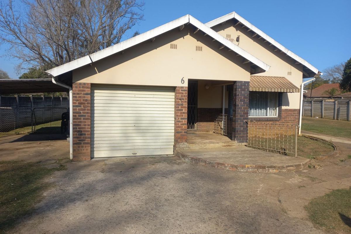 Front elevation of a single-story house featuring a garage, concrete driveway, and brick facade with a covered entrance area.