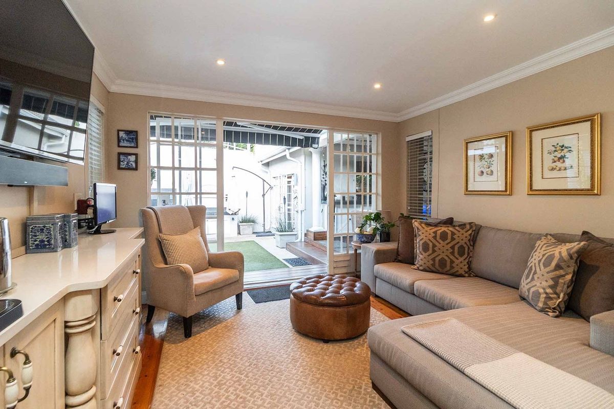 A cozy living room featuring recessed lighting, crown molding, and large glass-paned sliding doors that open onto a private rear patio area.