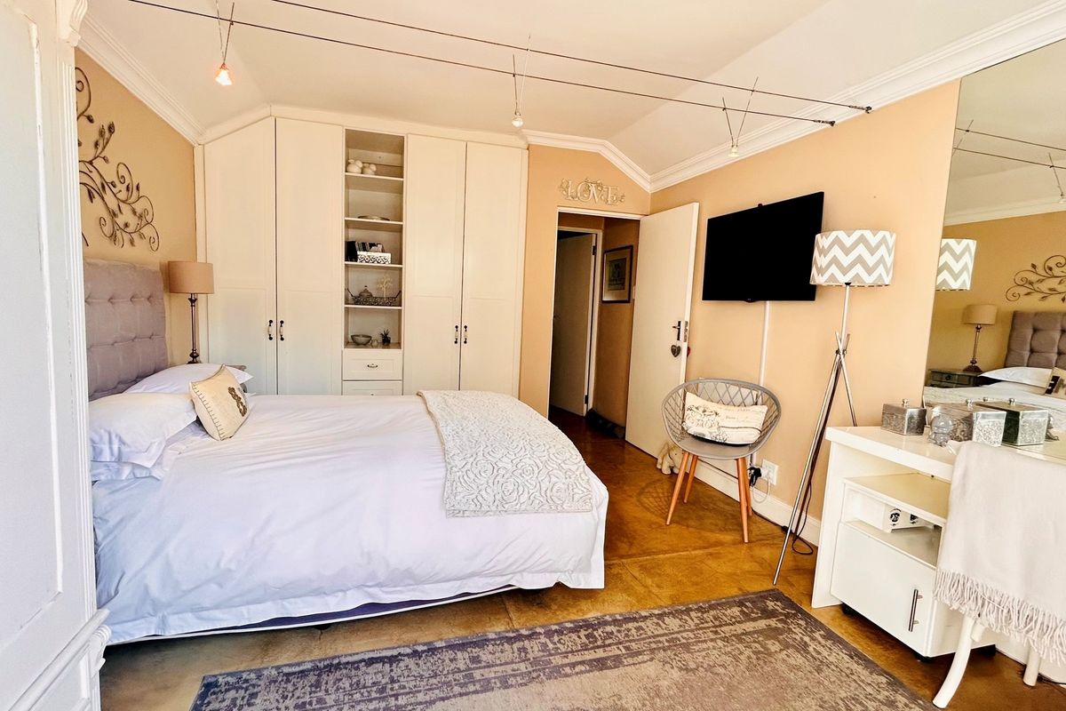 A well-maintained bedroom featuring built-in floor-to-ceiling cabinetry with integrated shelving, crown molding, and cable lighting system.