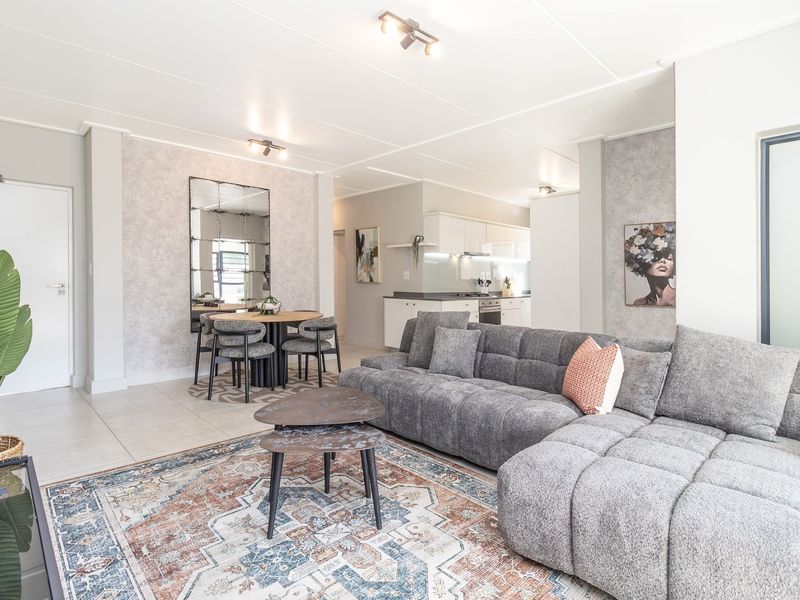 An open-plan living and dining area featuring tiled flooring, modern lighting, and a seamless transition into a contemporary kitchen space.
