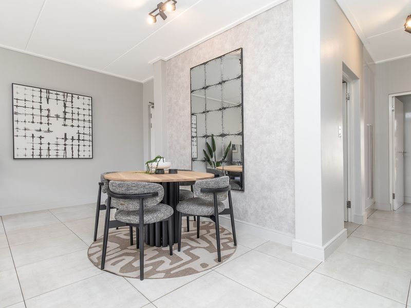 A bright and modern dining area featuring neutral tiled flooring, textured feature wallpaper, and contemporary track lighting.