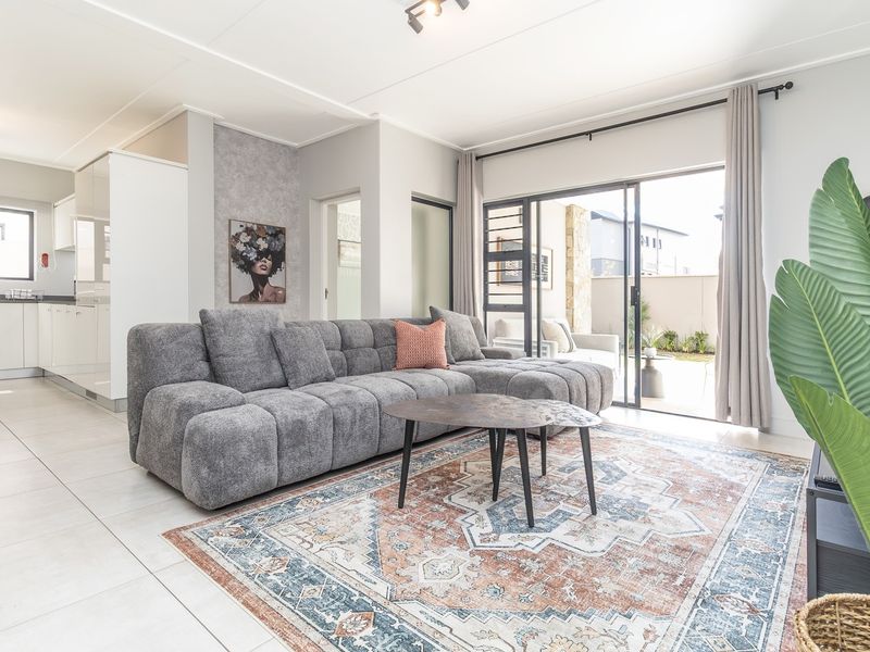 Bright open-plan living area featuring tiled flooring, modern kitchen cabinetry, and sliding glass doors leading to a private patio.
