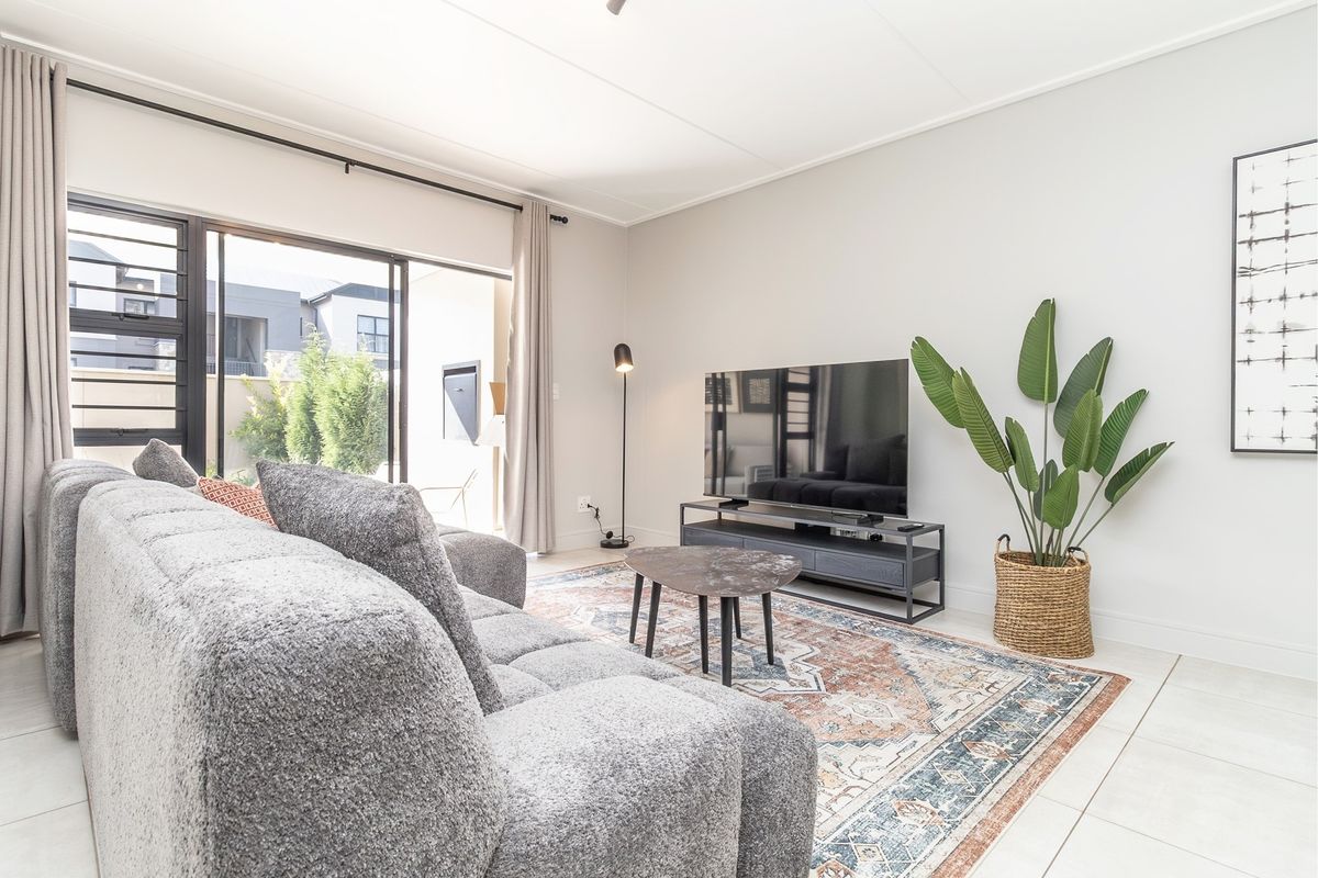 A bright and modern living room featuring large sliding glass doors that provide seamless access to the outdoor patio area.