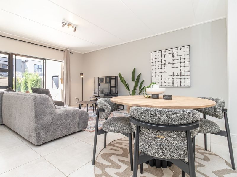 Bright open-plan living and dining area featuring large sliding glass doors that provide access to the outdoor space.
