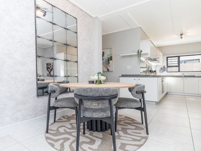 An open-plan dining and kitchen area featuring modern cabinetry, integrated appliances, tiled flooring, and a contemporary aesthetic.