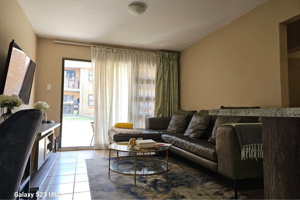 A comfortable living room featuring tiled flooring and a sliding glass door that provides access to an outdoor patio area.