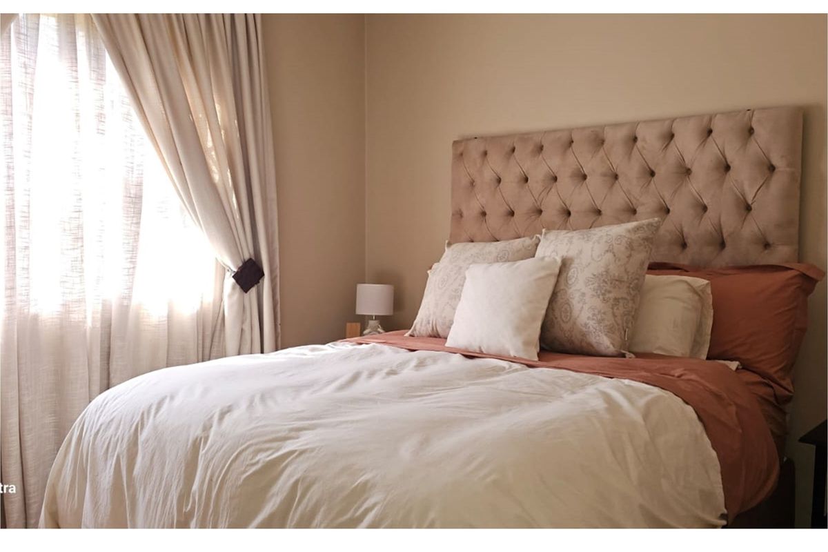 A cozy bedroom featuring neutral wall tones and natural light filtering through window treatments.