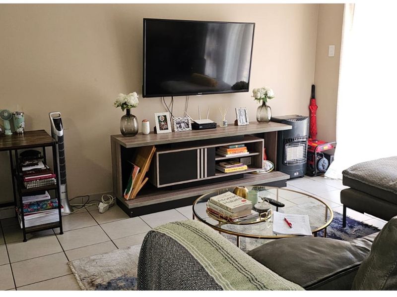 A living room area featuring tiled flooring and a wall-mounted television setup.