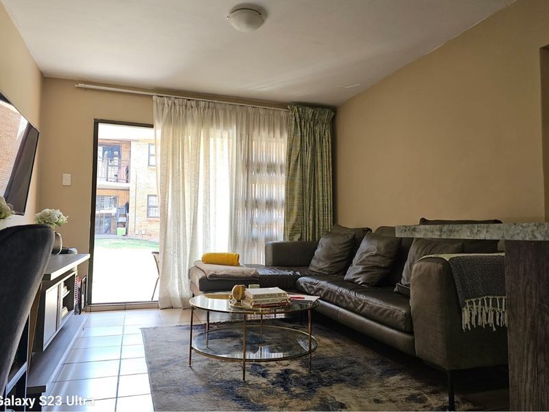 A comfortable living room featuring tiled flooring and a sliding glass door that provides access to an outdoor patio area.
