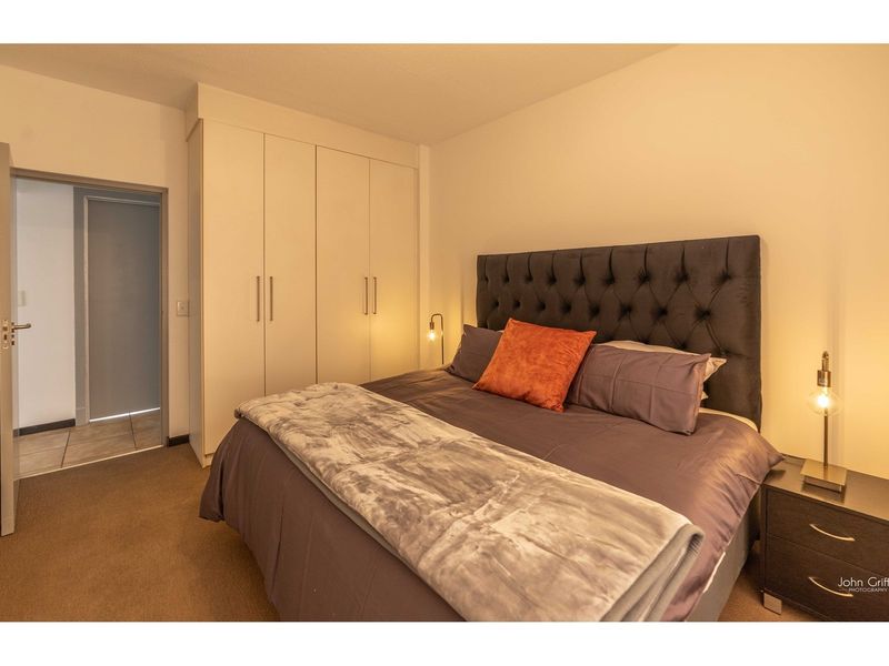 A well-maintained bedroom featuring neutral carpeting and ample built-in cupboard storage space.