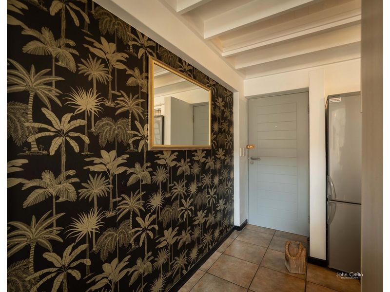 An entrance area featuring tiled flooring, exposed beam ceilings, and a decorative palm-print feature wall.