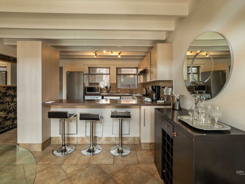 Open-plan kitchen featuring a breakfast bar, granite countertops, and exposed ceiling beams, seamlessly integrated into the living space.