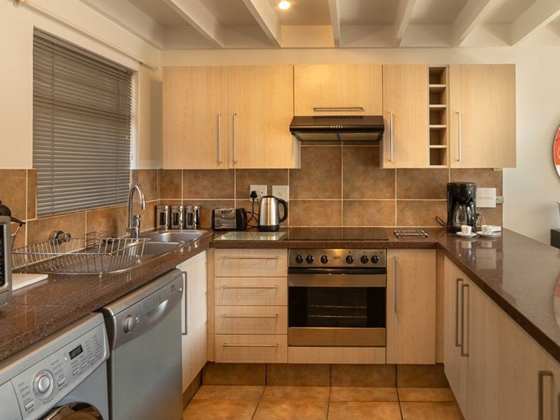 Functional kitchen featuring light wood cabinetry, granite-look laminate countertops, ceramic tile backsplash, and integrated appliances including an oven and hob.
