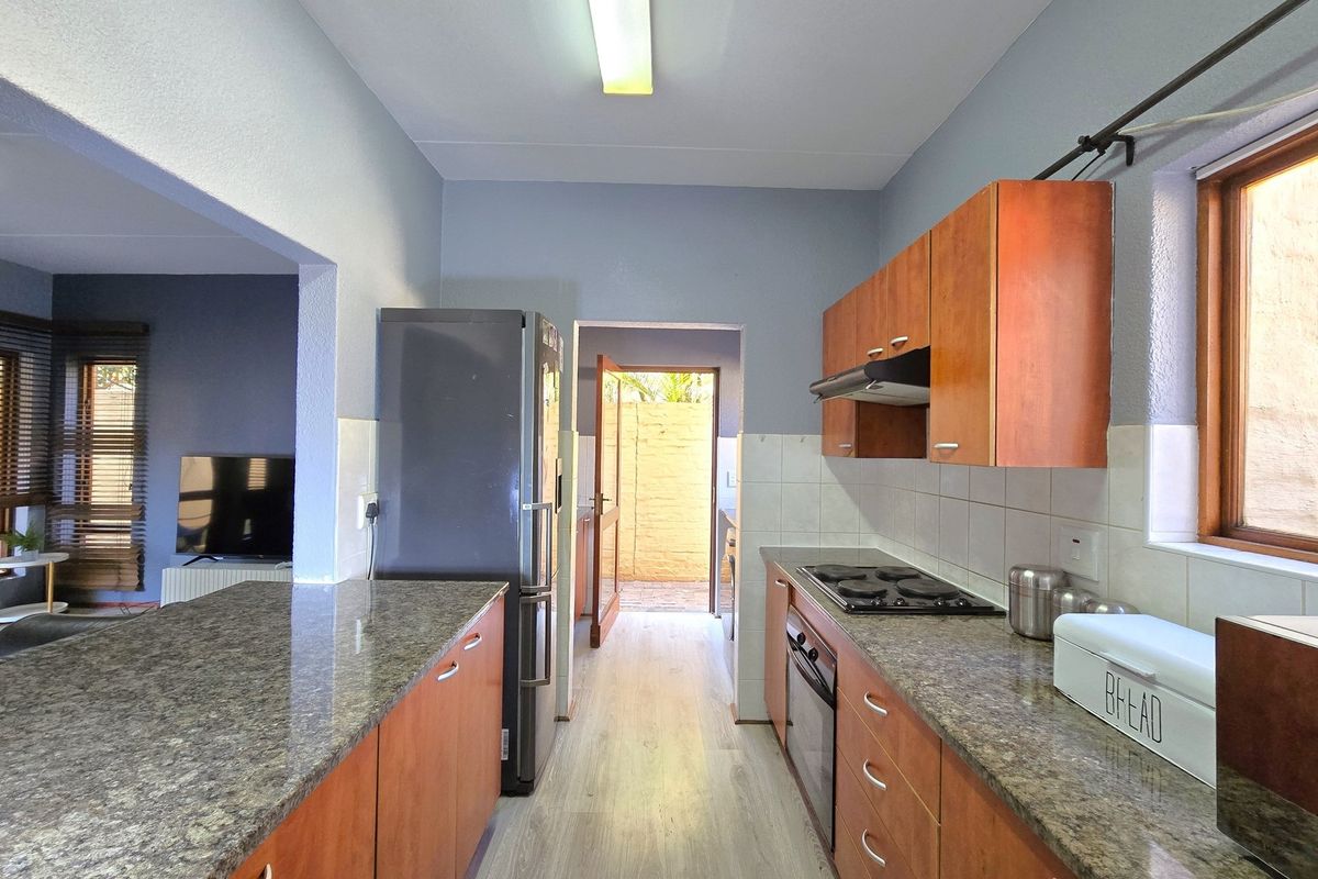 Functional kitchen featuring granite countertops, wooden cabinetry, built-in oven and hob, with direct access to an outdoor area.