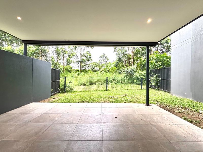 A spacious covered patio featuring tiled flooring and recessed lighting, overlooking a private rear garden area with perimeter fencing.