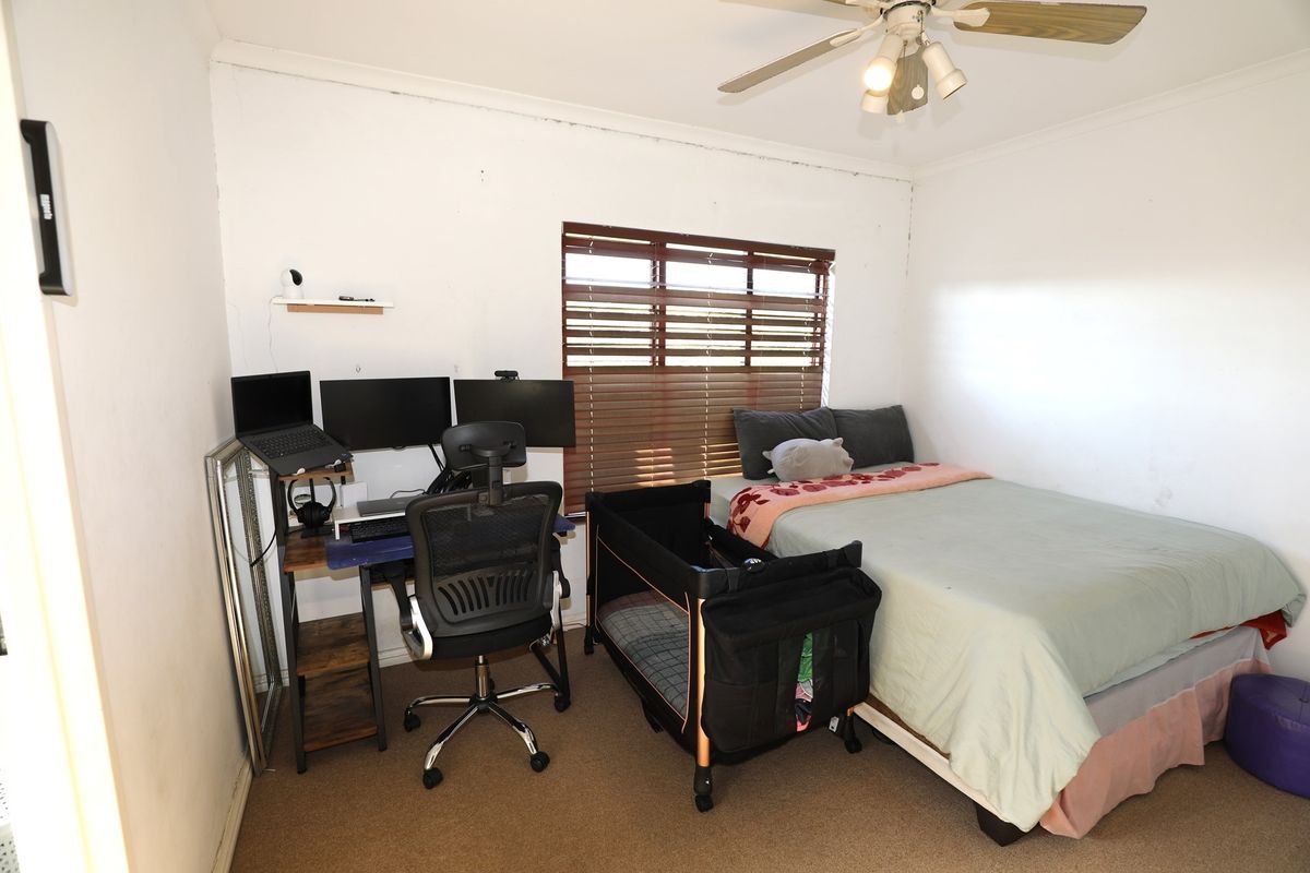A functional bedroom featuring a ceiling fan, carpeted flooring, and horizontal window blinds.