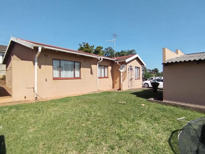 Rear view of the house featuring a tiled roof, exterior wall finish, and a private garden area.
