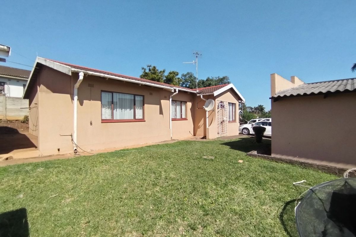 Rear view of the house featuring a tiled roof, exterior wall finish, and a private garden area.