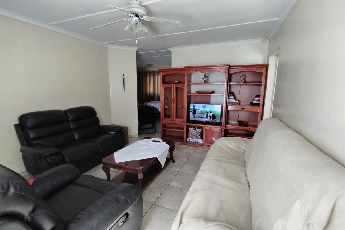 A living room featuring tiled flooring, a ceiling fan, and a built-in wooden shelving unit, offering a functional and comfortable living space.