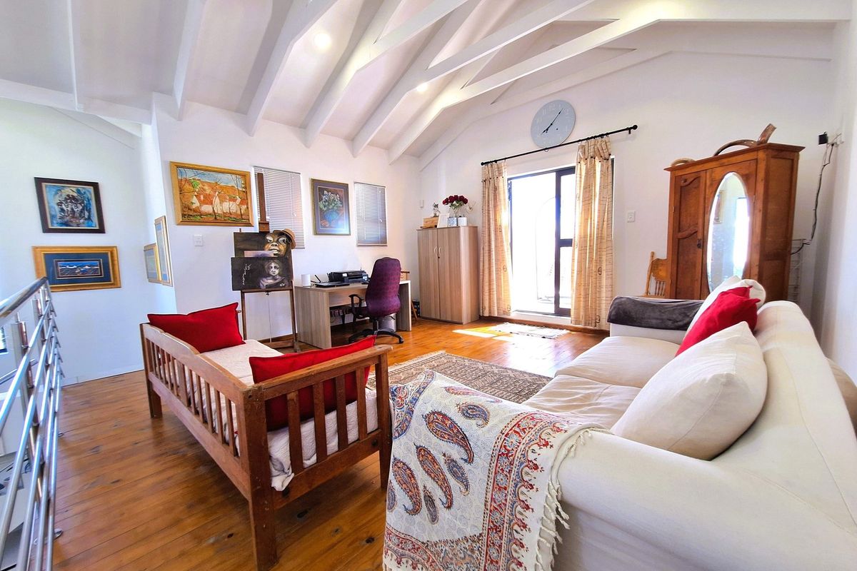 Spacious living area featuring high vaulted ceilings with exposed beams, warm timber flooring, and direct access to an outdoor balcony.