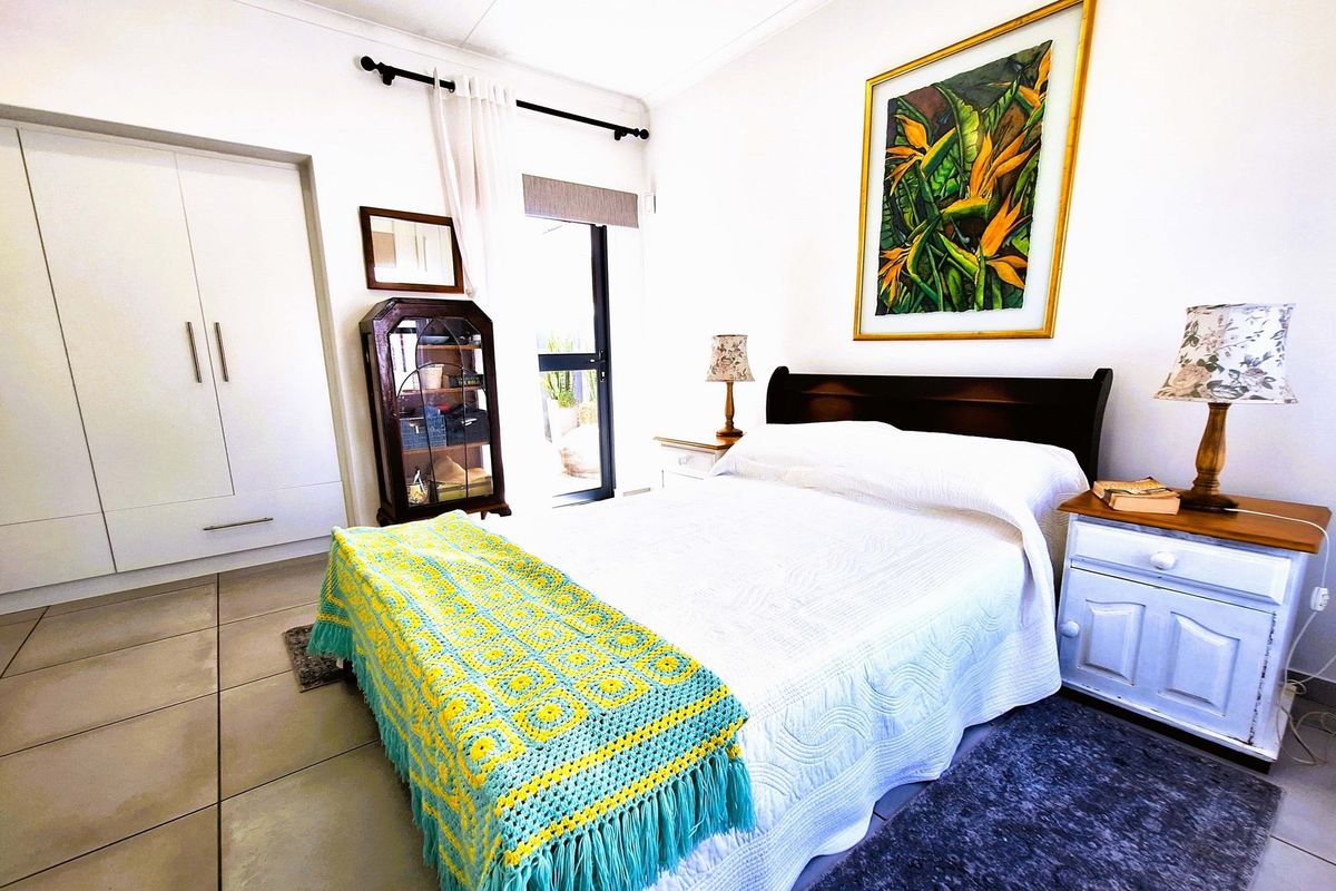 A bright bedroom featuring built-in cupboards, tiled flooring, and a glass door providing access to the exterior.