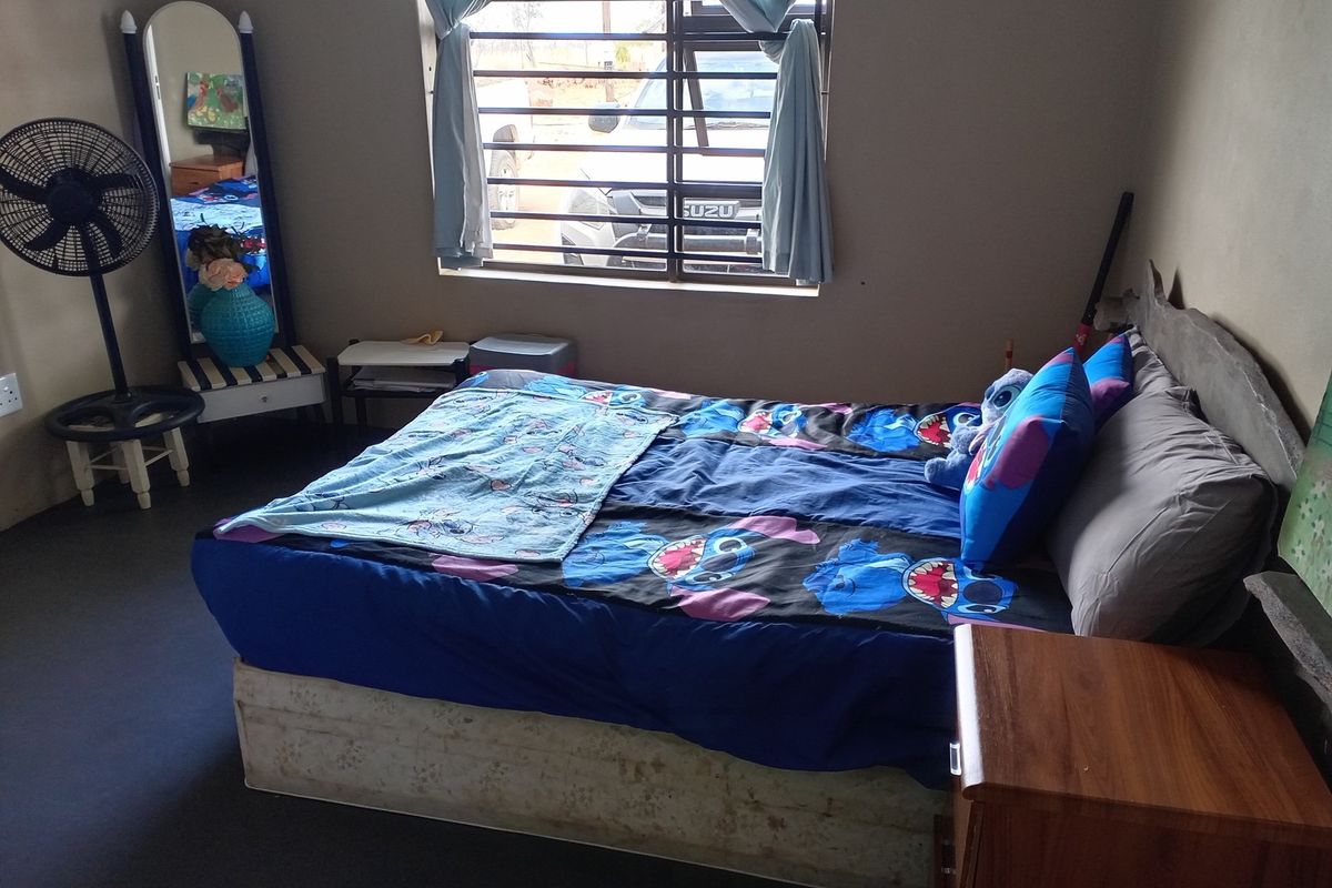 A functional bedroom featuring a window with security bars and neutral wall finishes.