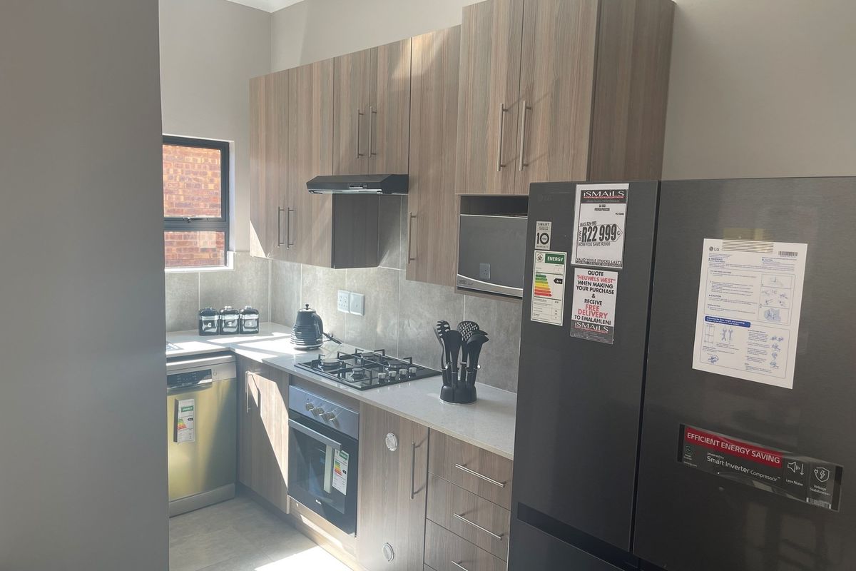 Modern kitchen featuring wood-grain cabinetry, stone countertops, built-in gas hob, oven, and extractor fan with tiled splashbacks.