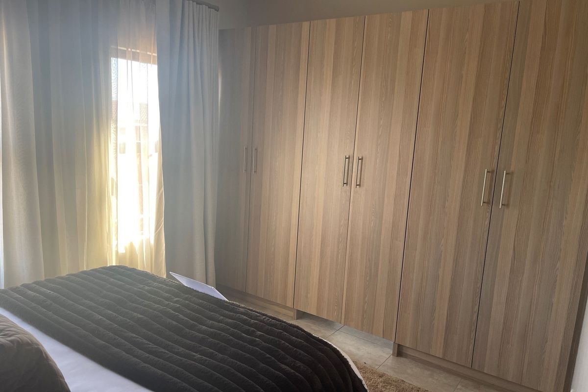 A well-lit bedroom featuring extensive floor-to-ceiling built-in wooden cabinetry providing ample storage space.