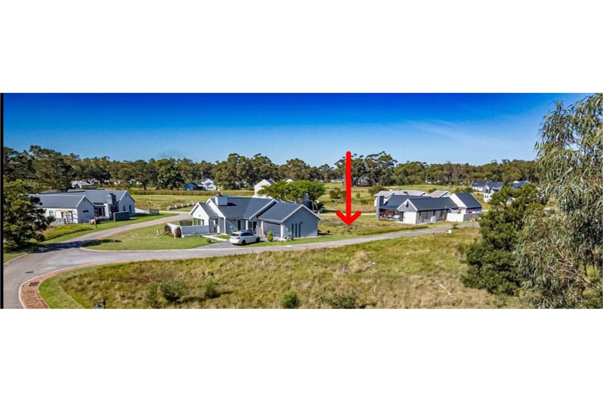 An aerial view of a vacant residential plot situated within a developed estate, featuring road access and surrounding established homes.