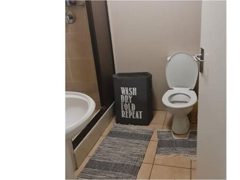 A functional bathroom featuring a pedestal basin, a shower enclosure, and a standard toilet with tiled flooring.