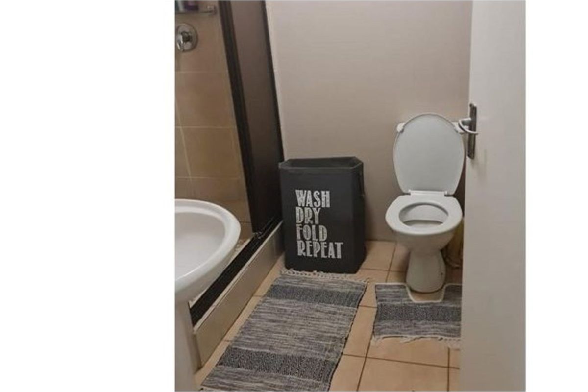 A functional bathroom featuring a pedestal basin, a shower enclosure, and a standard toilet with tiled flooring.