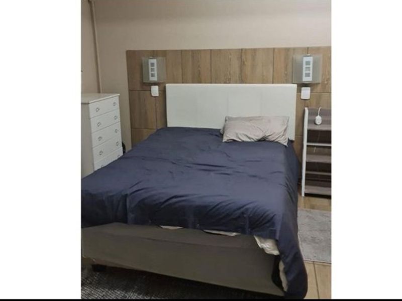 A bedroom featuring a wood-look feature headboard panel with integrated wall-mounted lighting fixtures.