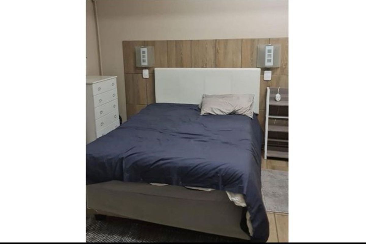 A bedroom featuring a wood-look feature headboard panel with integrated wall-mounted lighting fixtures.